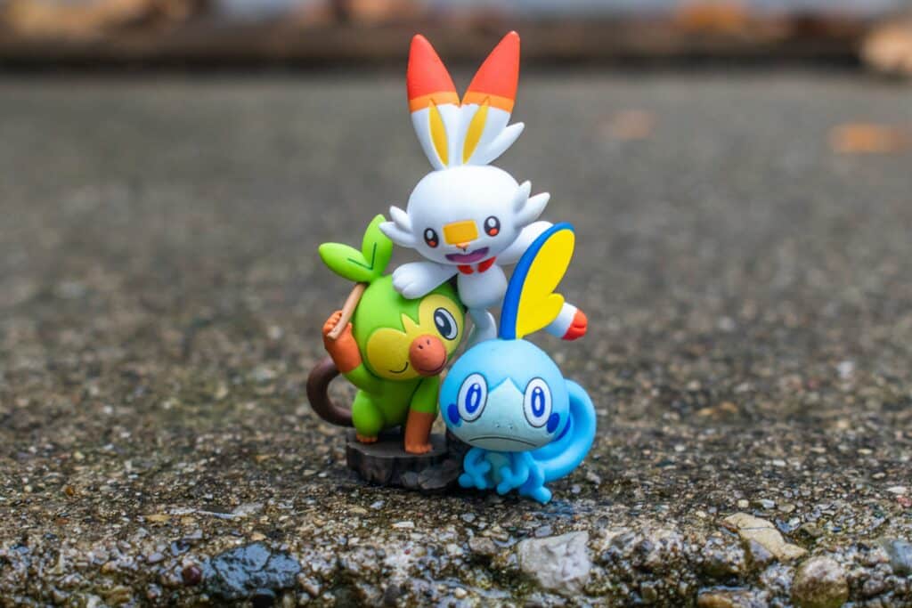 Drie pokemon speelgoedfiguren staan samen op nat asfalt en vormen een kleurrijk groepje met herkenbare details.