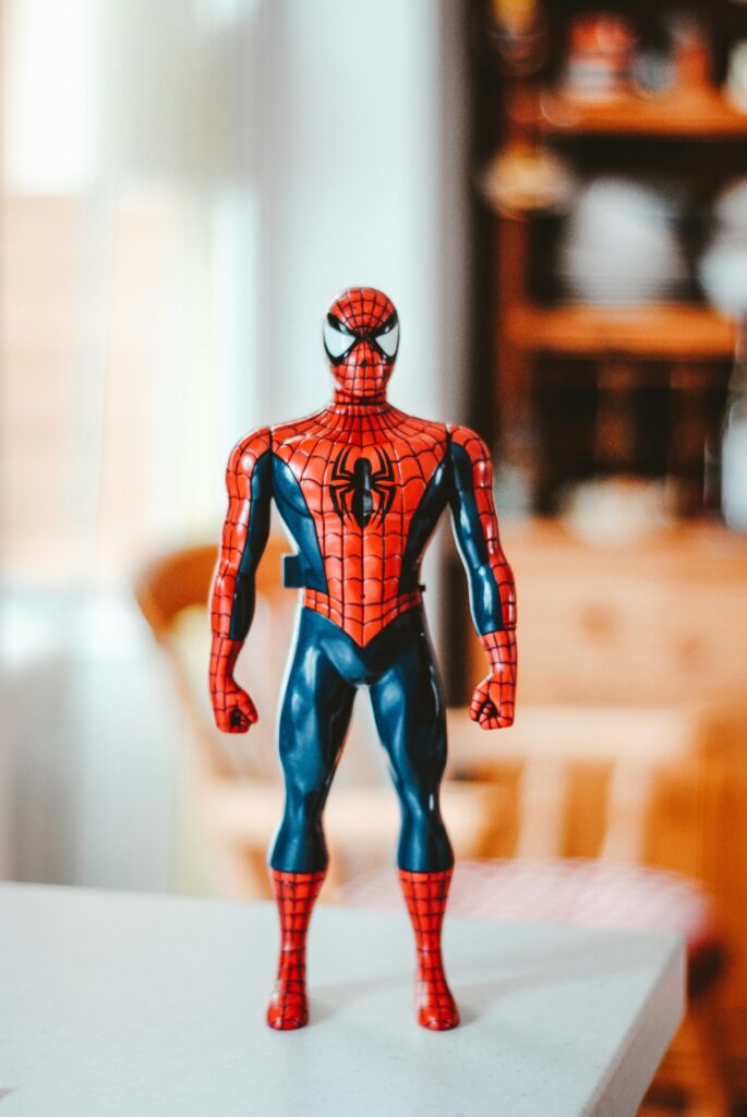 Een Spider Man actiefiguur staat rechtop op een tafel binnenshuis en is scherp zichtbaar tegen een wazige achtergrond.
